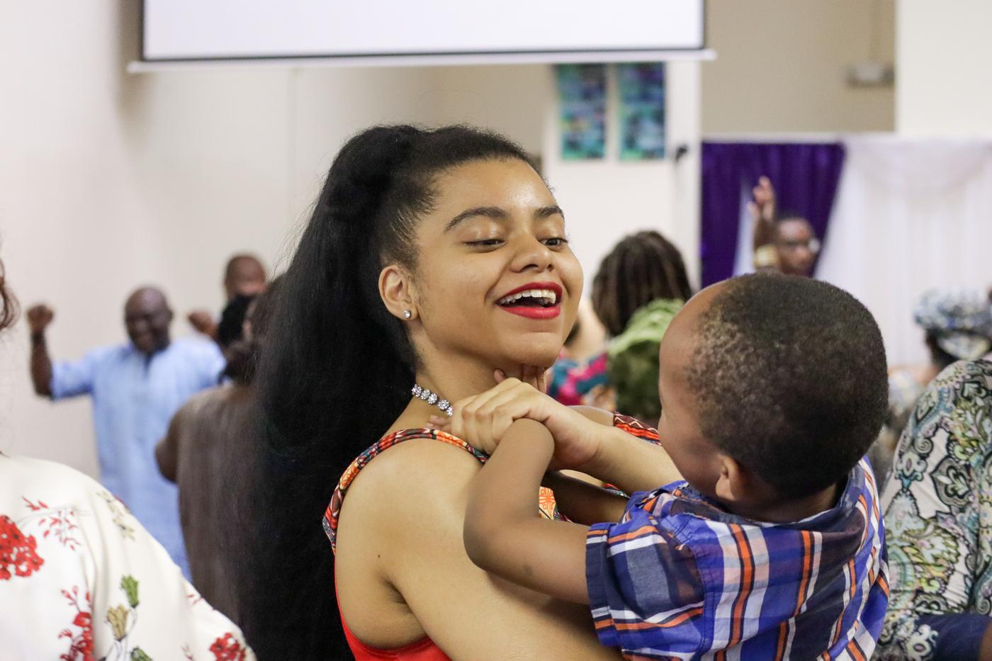 Young woman laughing while holding a child during service